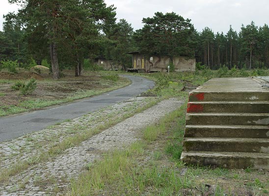 Dreier-Ensemble. Füllhäuser der Wehrmacht zur Füllung von Granaten für Feldhaubitzen. Auffällig hierbei das erhöhte Betongrundfundament welches erstens die Logistik des Be- und Entladens erleichterte und zweitens im Falle eines Bodenbrandes das Lagergut entsprechend gut schützte. Dreier-Ensemble. Füllhäuser der Wehrmacht zur Füllung von Granaten für Feldhaubitzen. Auffällig hierbei das erhöhte Betongrundfundament welches erstens die Logistik des Be- und Entladens erleichterte und zweitens im Falle eines Bodenbrandes das Lagergut entsprechend gut schützte.